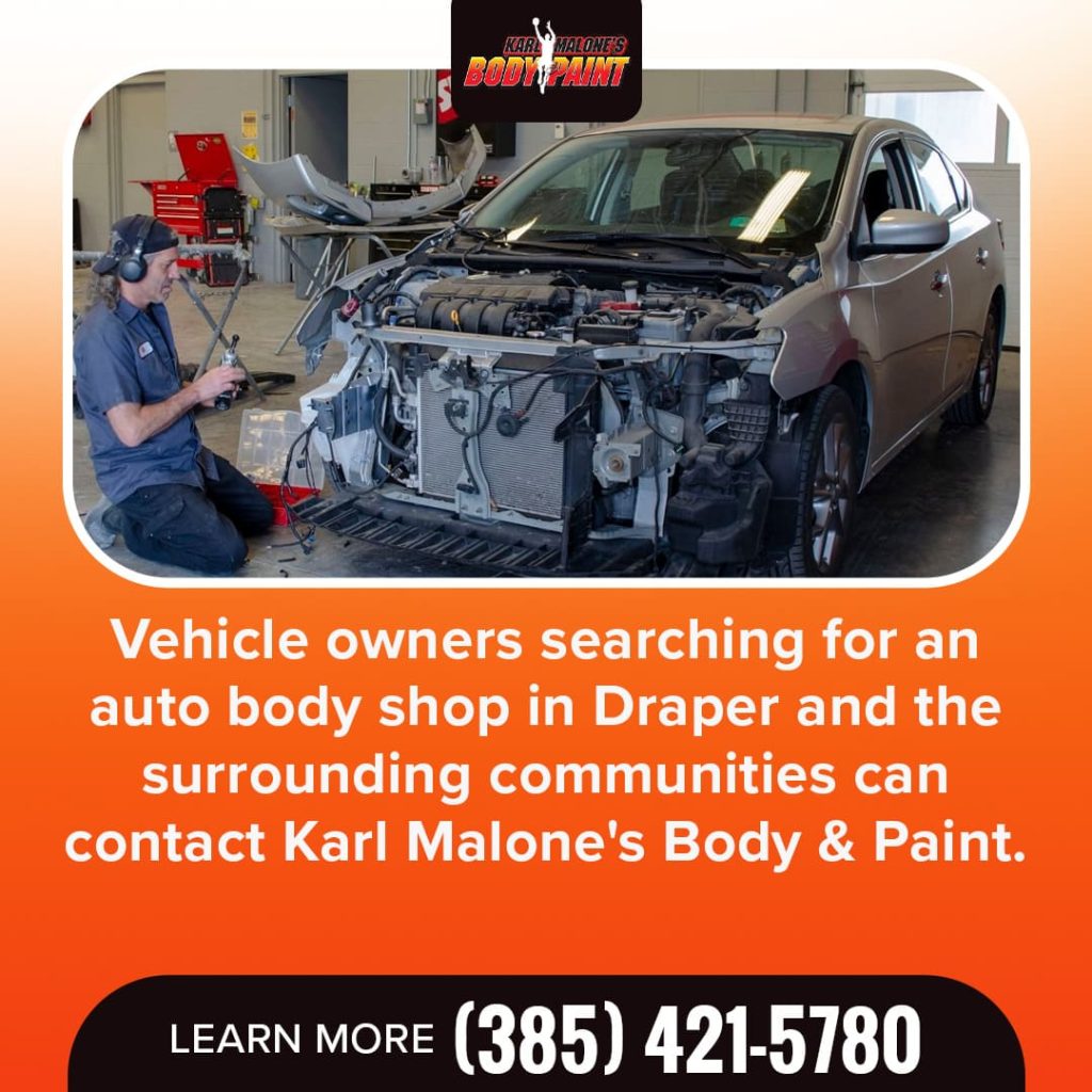 A Karl Malone's Body & Paint technician working on the front end of a silver car with visible damage, demonstrating expert auto body repair services.