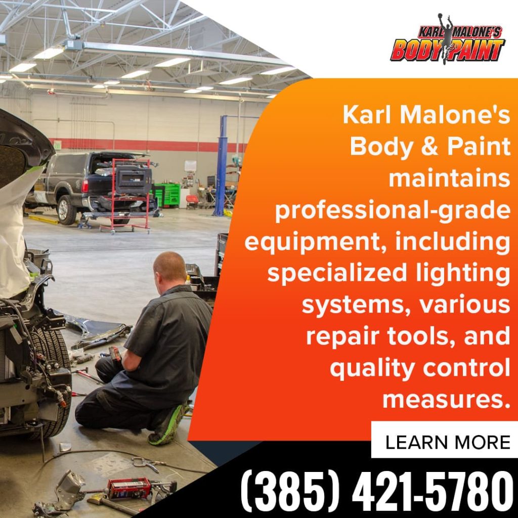 A technician at Karl Malone's Body & Paint working on a car in a spacious, well-equipped facility, demonstrating the use of professional-grade repair tools and specialized lighting.