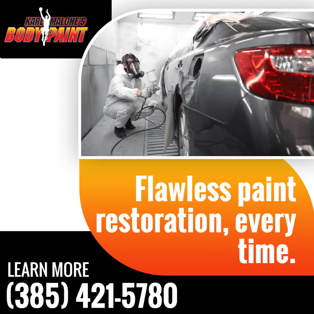 A professional wearing a respirator and protective suit performs flawless paint restoration on a gray car in a dedicated paint booth.